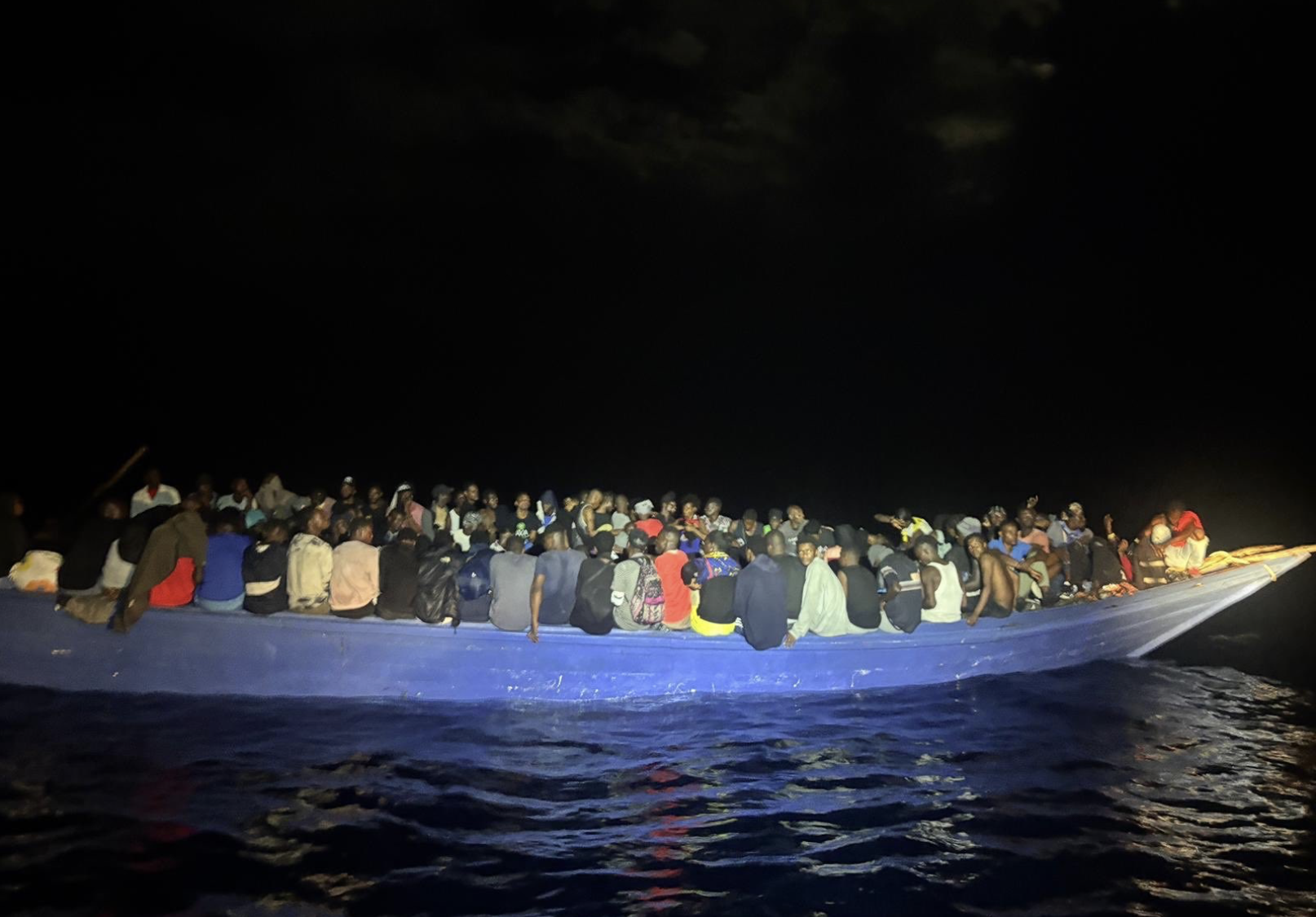 dozens of people sit on a boat on a dark morning
