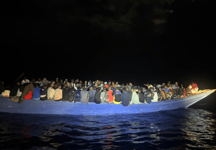 dozens of people sit on a boat on a dark morning