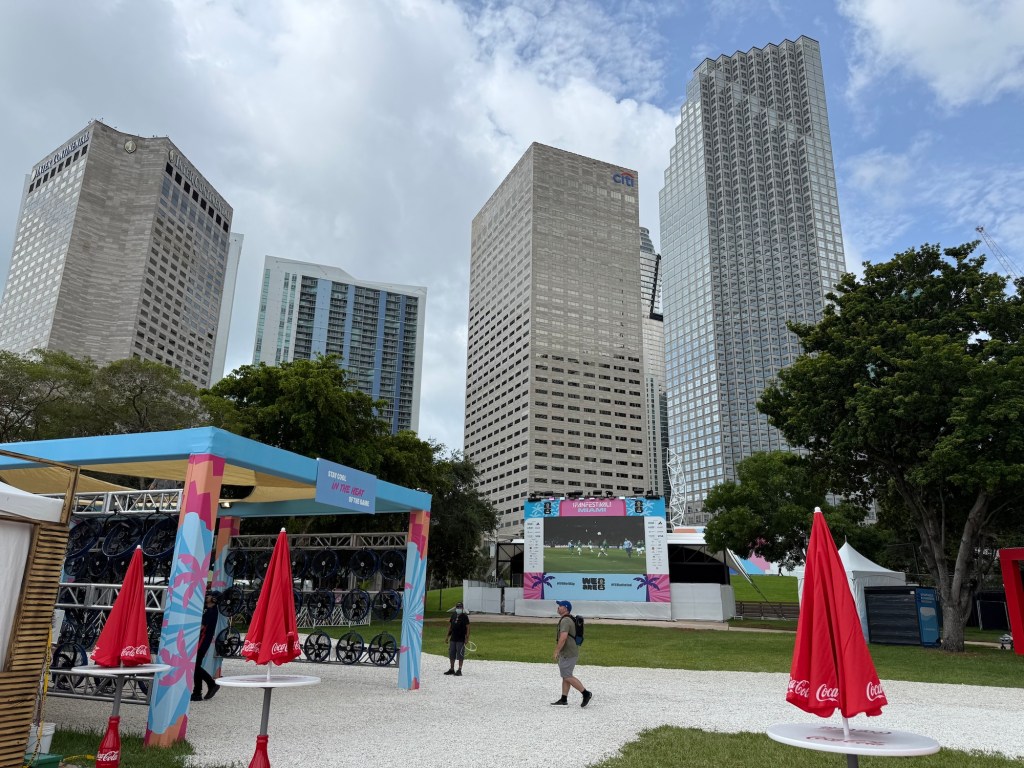 photo of an LED screen in an outdoor park flanked by skyscrapers