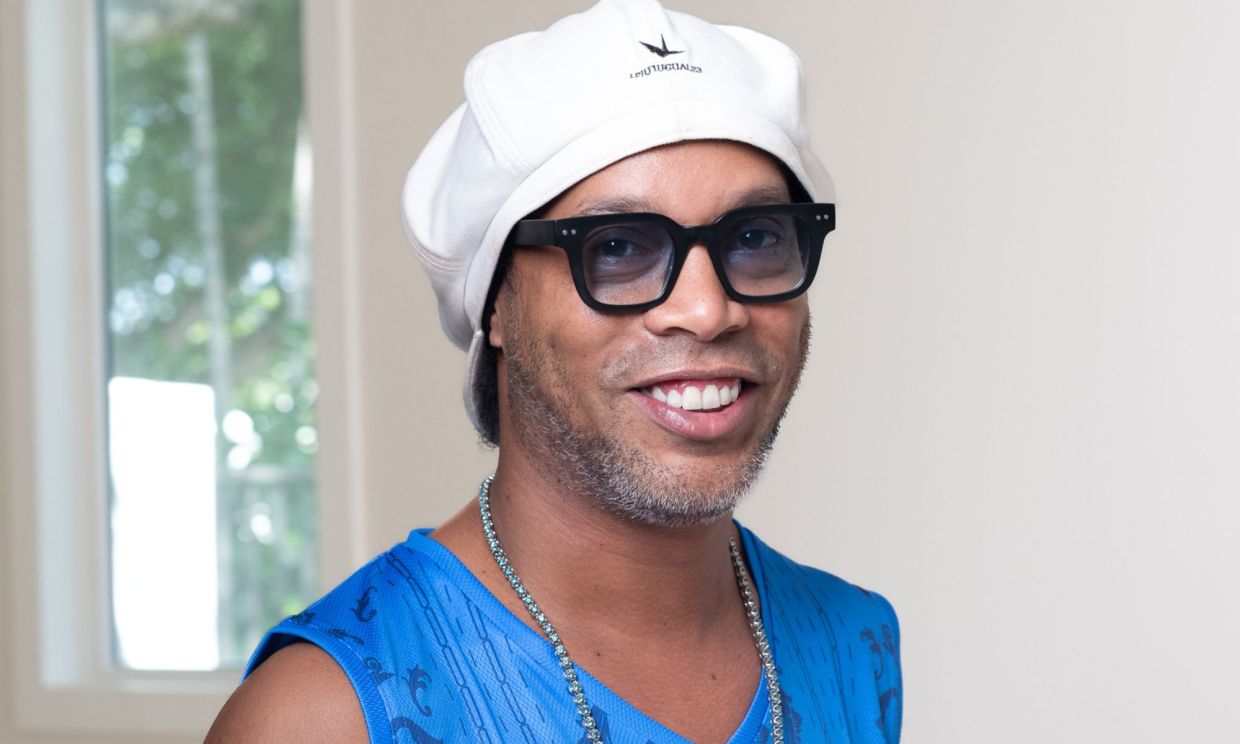 Photo of Ronaldinho wearing a white hat and a light blue shirt.