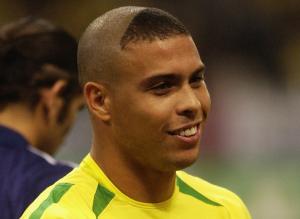 Brazilian soccer player Ronaldo Nazário smiles on the field while sporting a triangle buzz cut