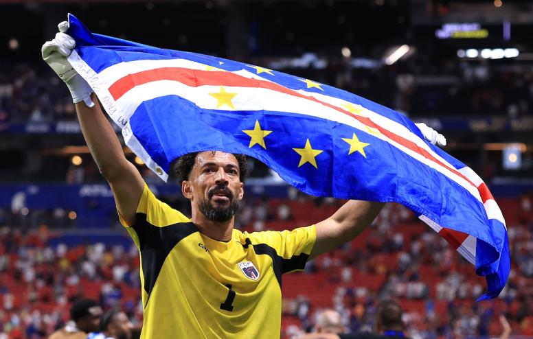 a professional soccer player holds up the Cabo Verdean national flag