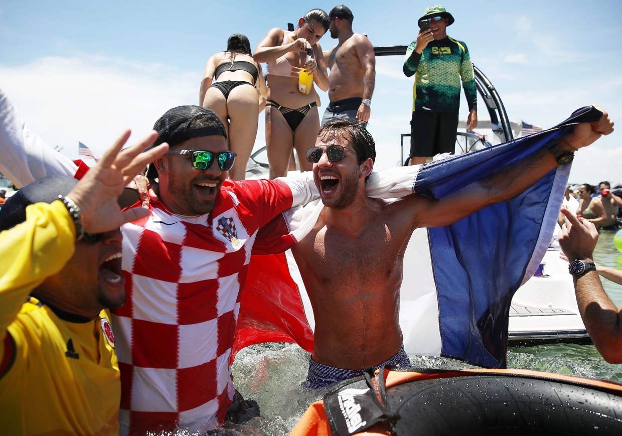 world cup fans in different team t-shirts party together in the ocean