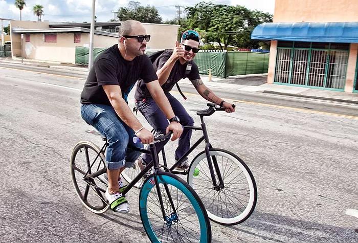 Two men ride bicycles on a Miami street