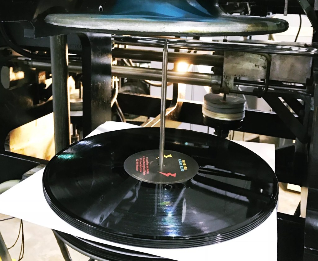 Photo of a vinyl record being pressed.