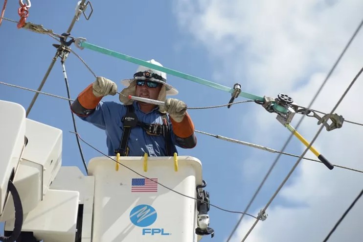 A utility employee works on a power line.
