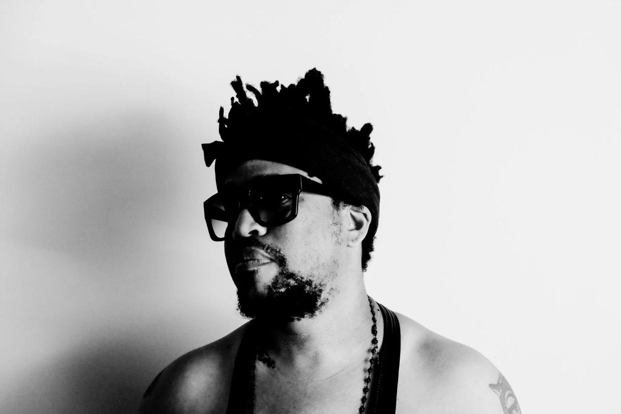 Black and white photo of a man wearing a black tank top and sunglasses.