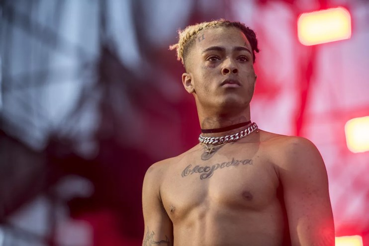 A color photo of popular and controversial local rapper XXXtentacion, head and torso, looking defiant, onstage at the 2017 Rolling Loud hip-hop festival in Miami
