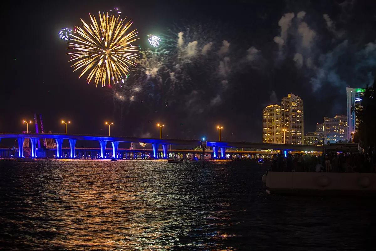 photo of fireworks over the water and a bridge in Miami