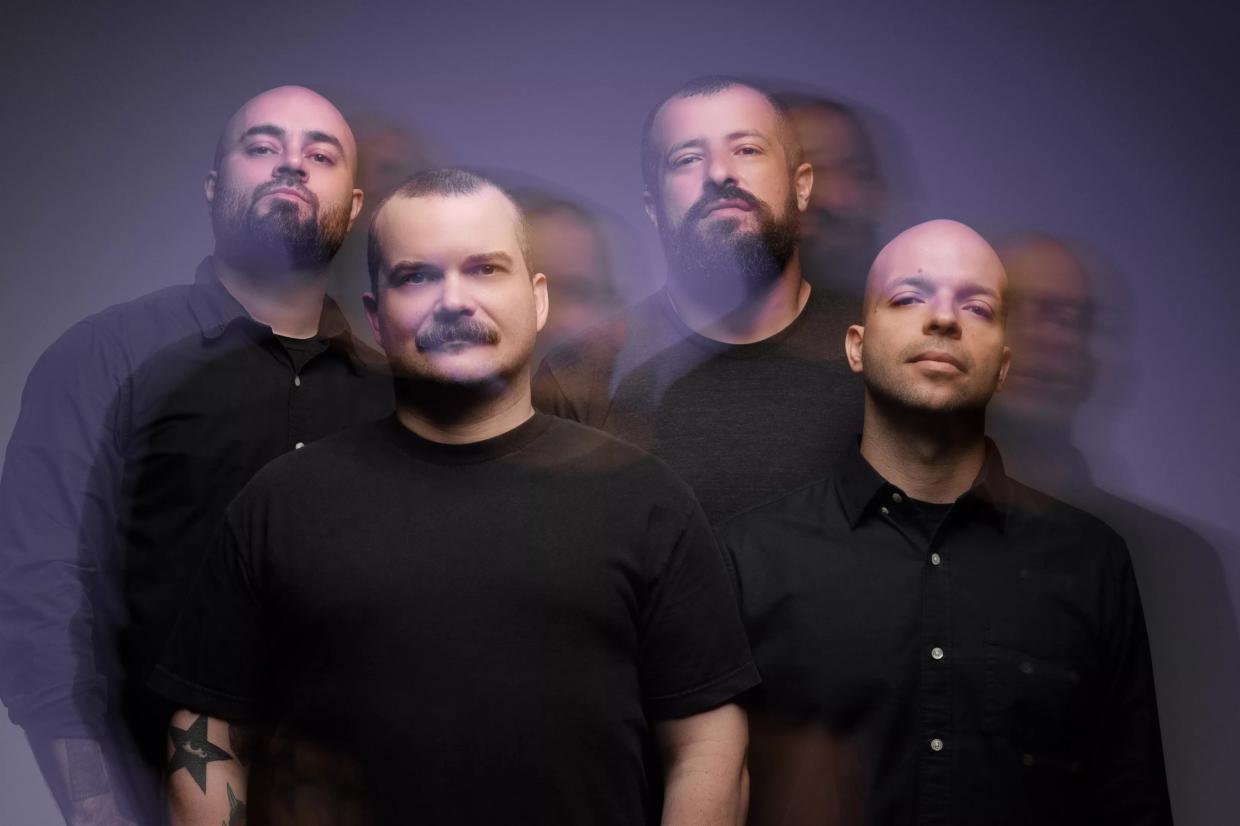 photo of four men looking at the camera wearing black shirts.