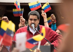 photo of Venezuelan President Nicolás Maduro making a speech, surrounded by hands holding the Venezuelan flag