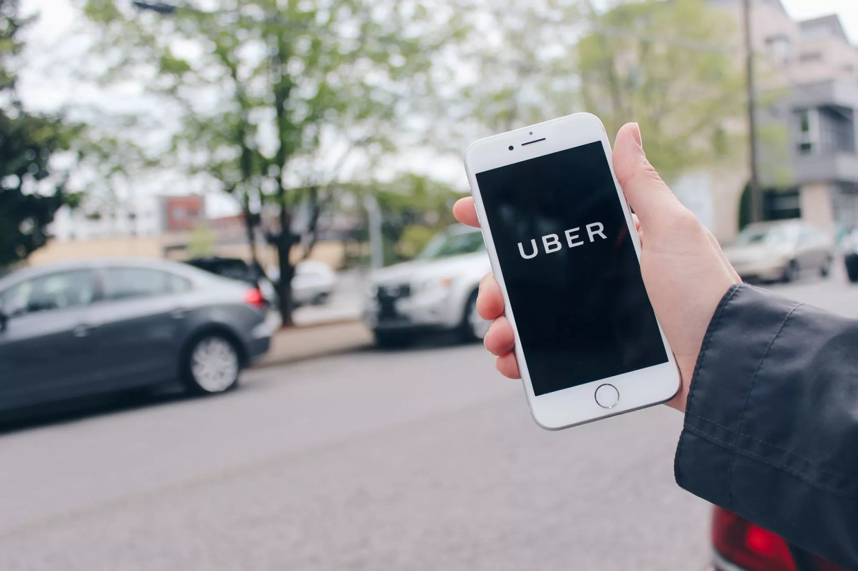 a hand holds up a phone with the Uber app on the screen