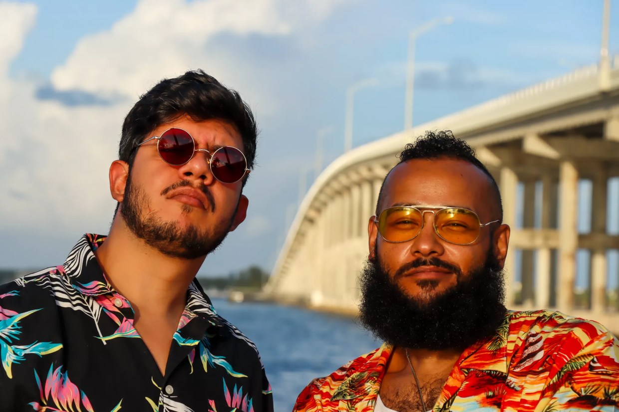 Two men wearing tropical shirts by a highway