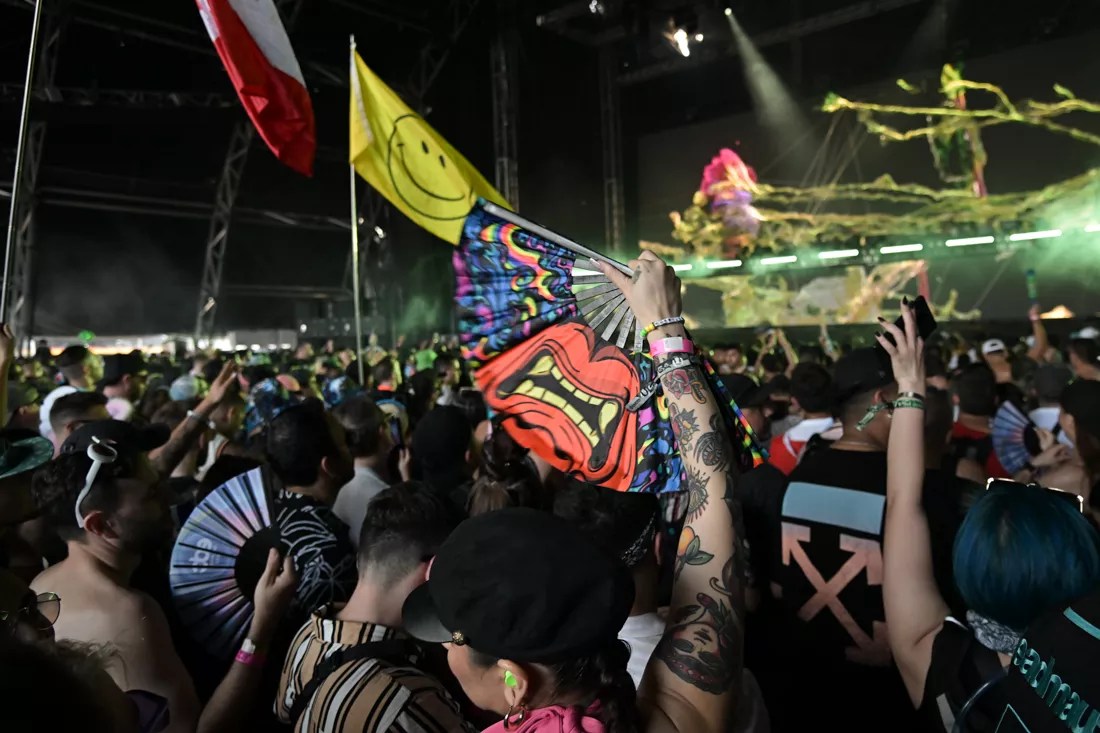 A festivalgoer holds up a colorful fan in the middle of the crowd.