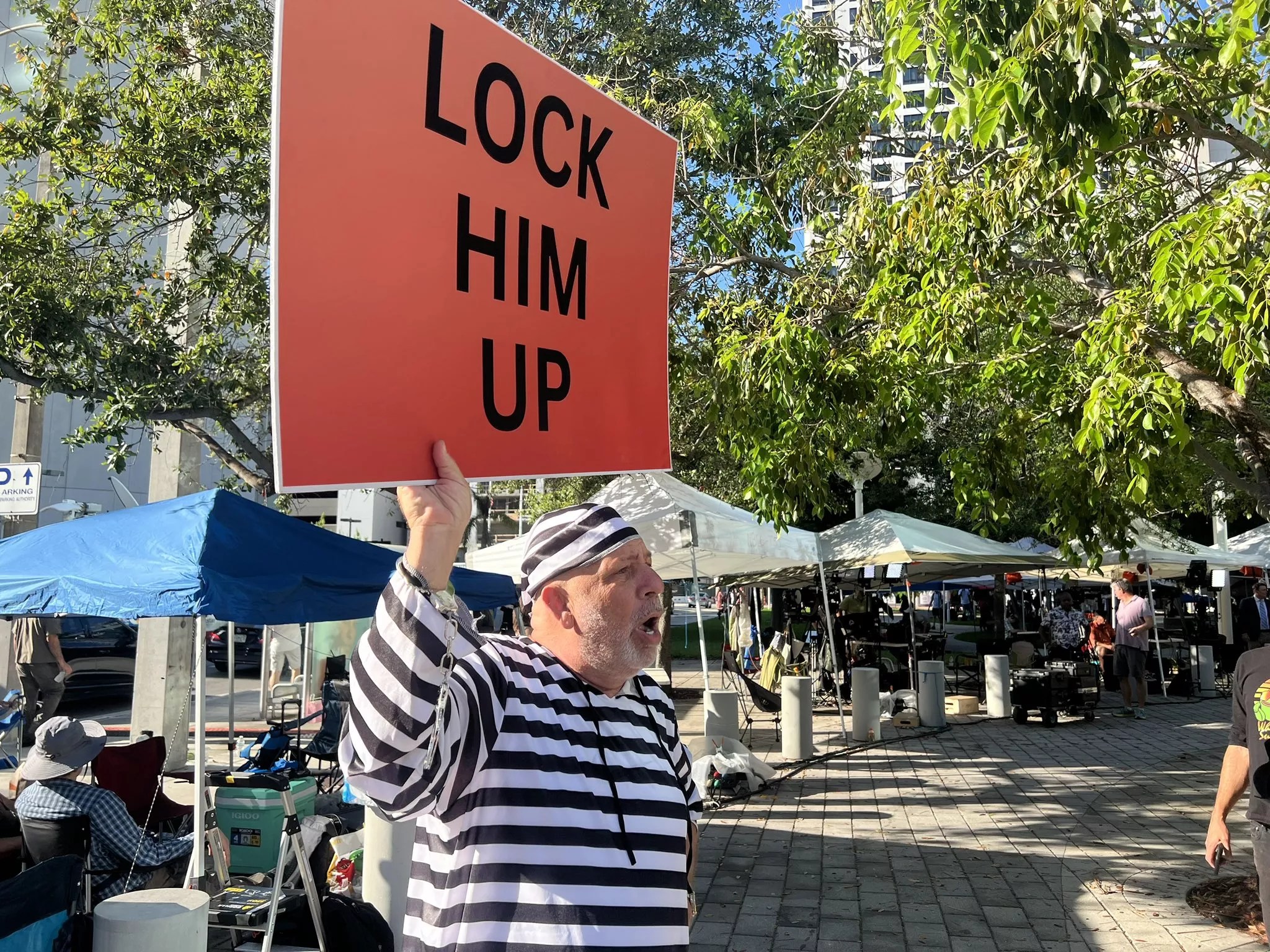 A man outside the Wilkie D. Ferguson Jr. U.S. Courthouse in downtown Miami holding a sign that reads "LOCK HIM UP"