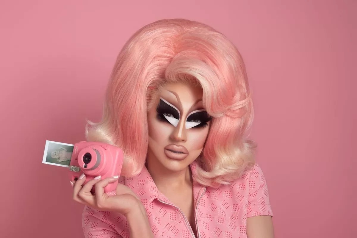 Trixie Mattel dressed in pink holding a camera
