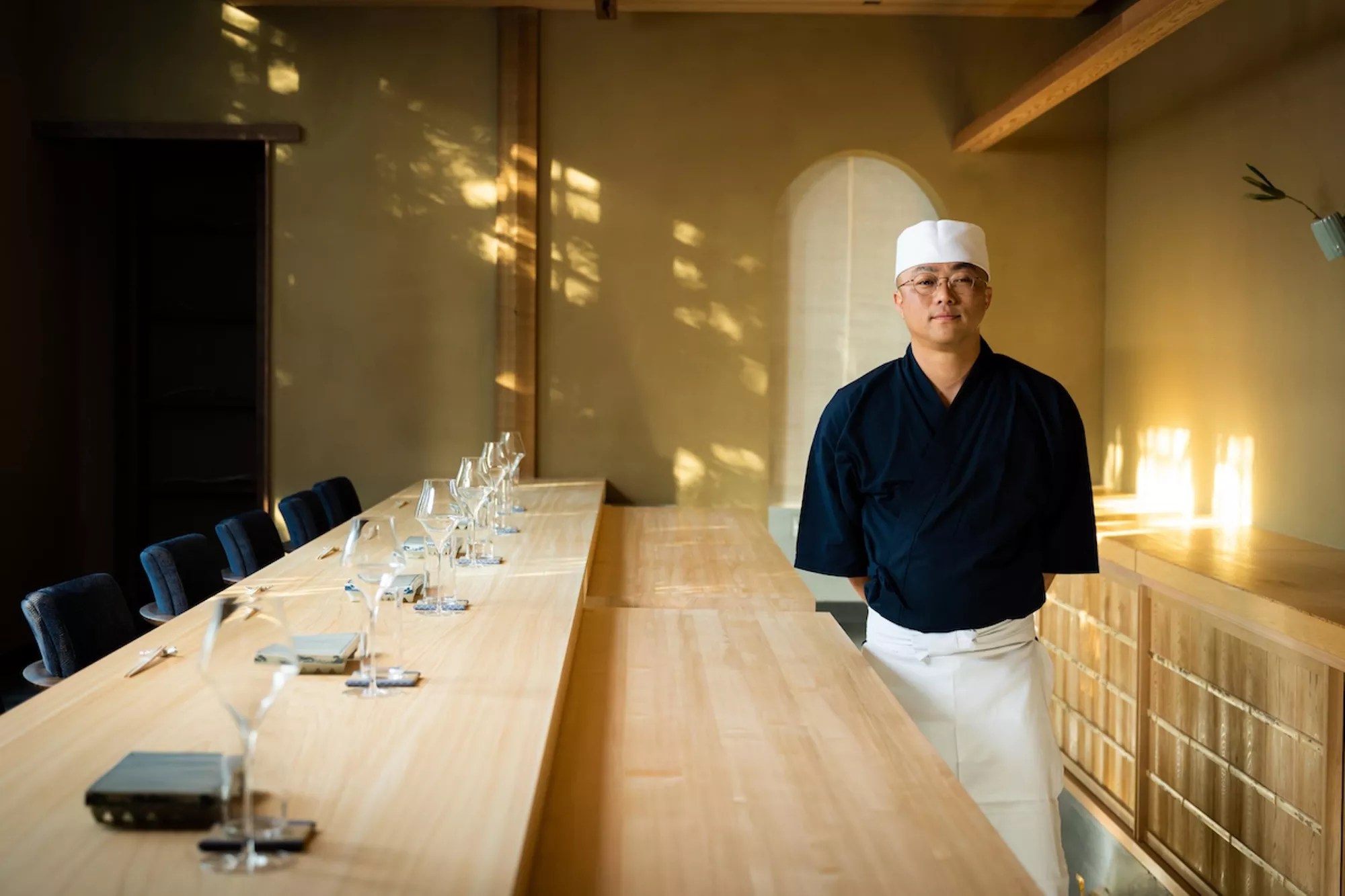 A sushi chef standing next to a sushi counter
