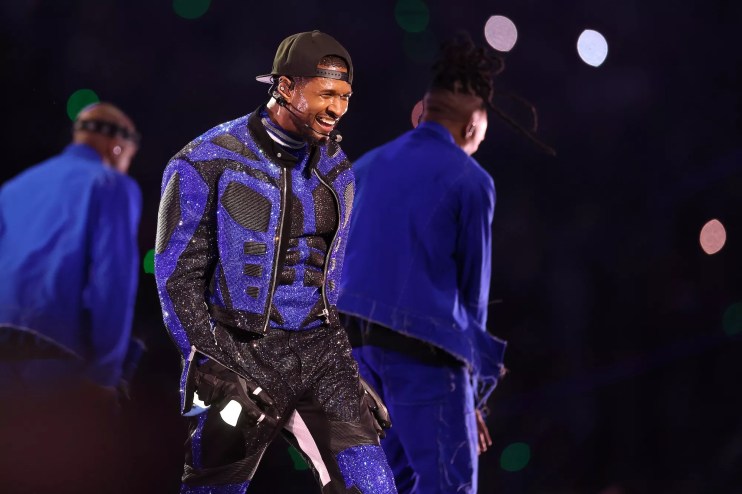 Usher performing onstage in a blue and black sequin outfit