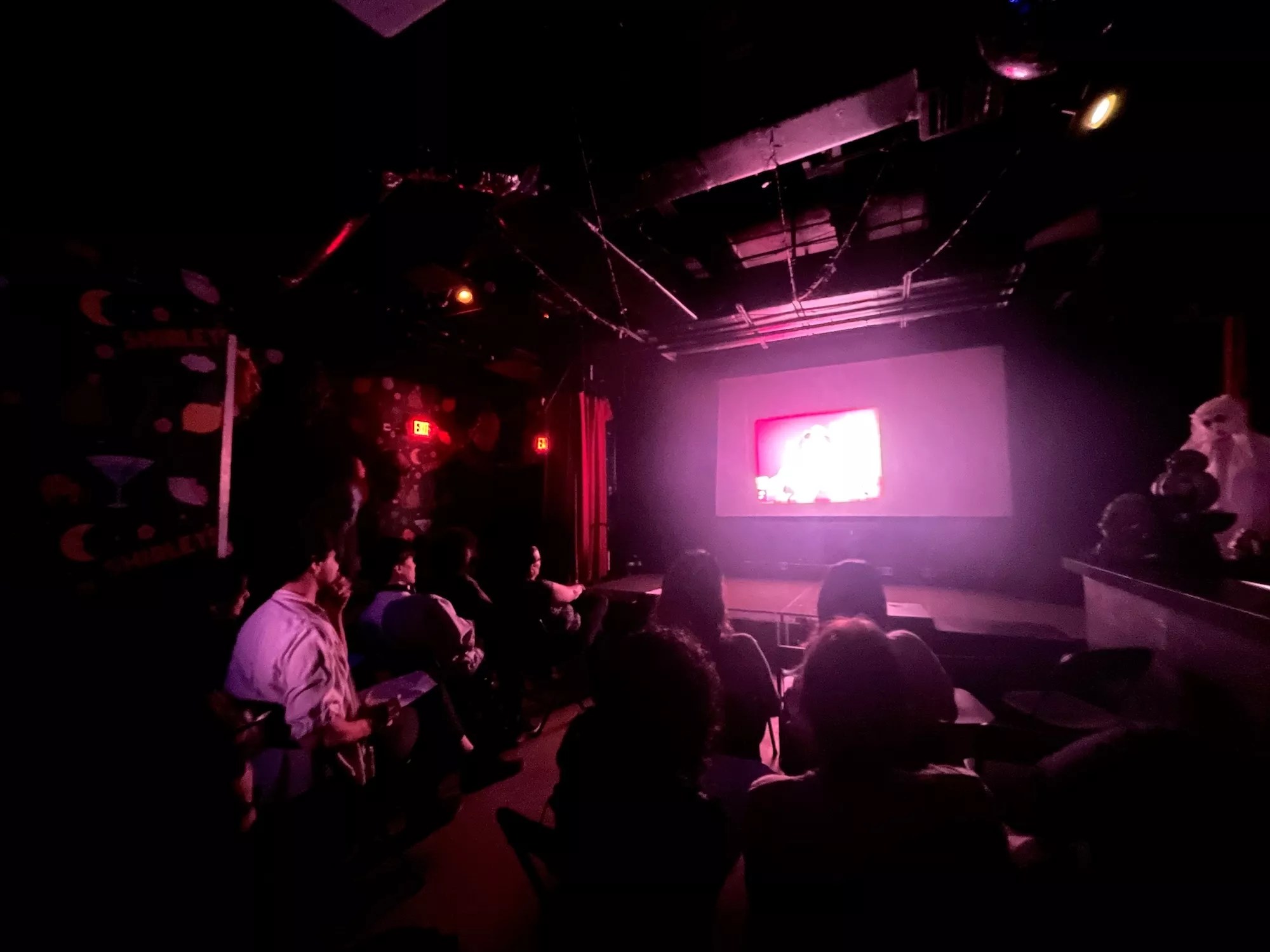 A group of people sitting in a dark room watching a film projection