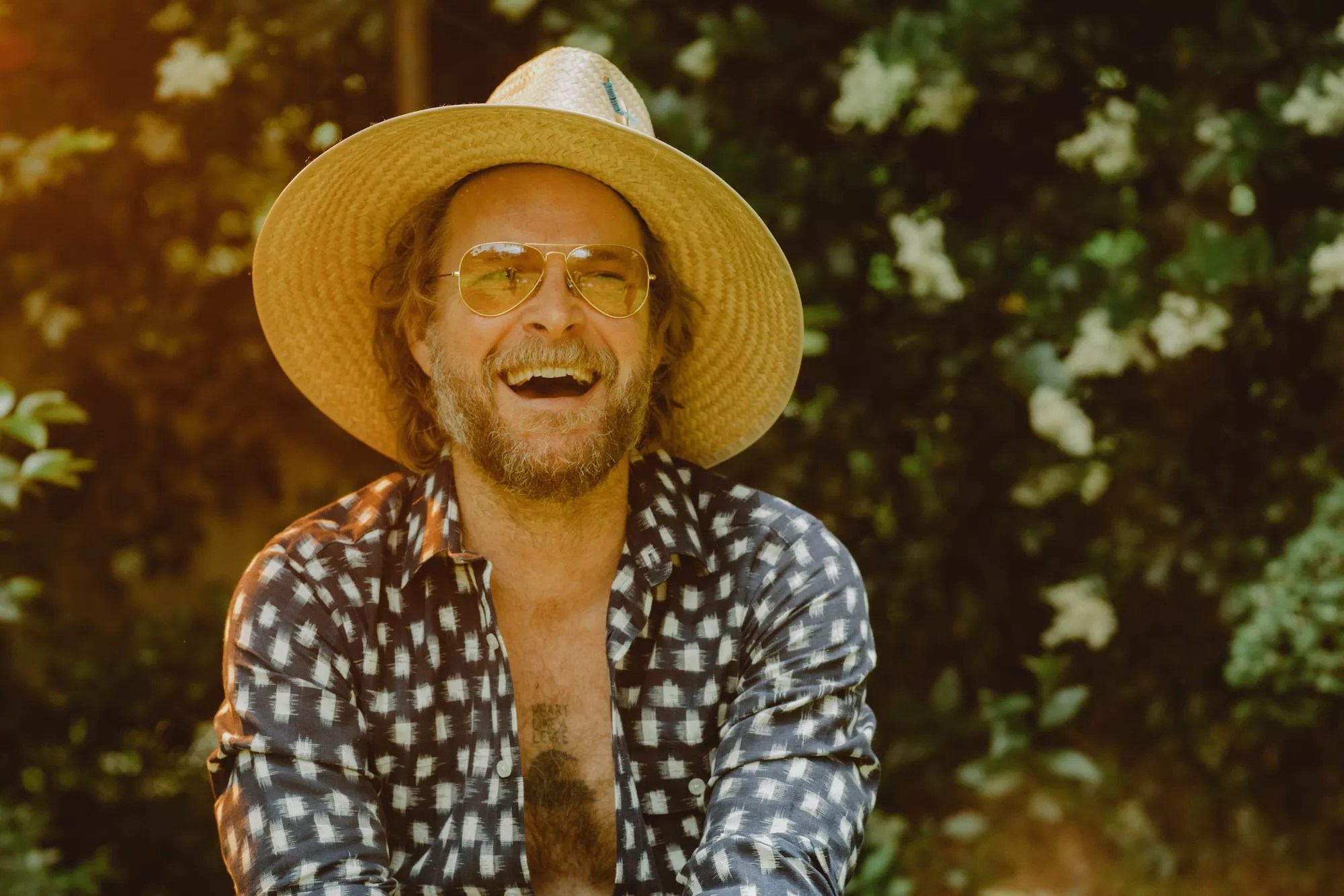 MC Taylor of Hiss Golden Messenger smiling and wearing a straw hat