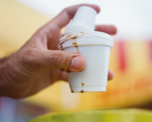 A hand holding a Styrofoam cup filled with Cuban coffee