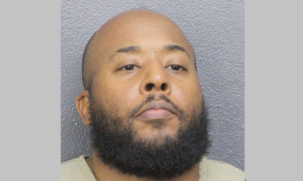 Frenel Cenat, a heavyset bearded police officer, is pictured in a mugshot after his extortion arrest