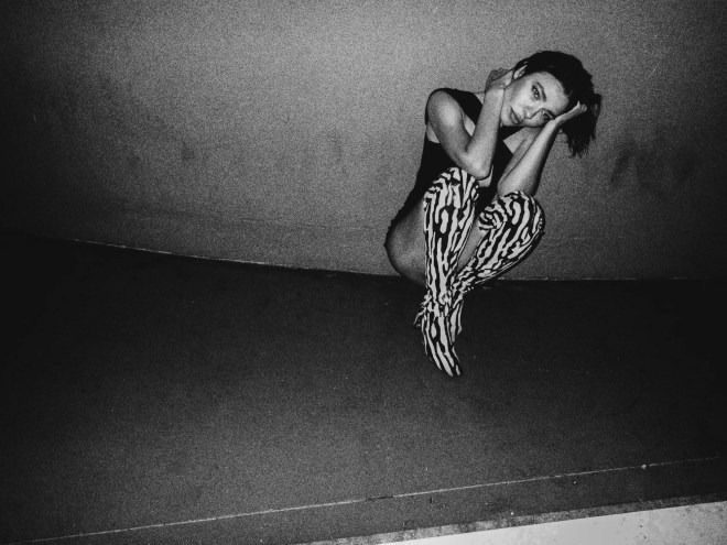 Nina Kraviz kneeling against a wall