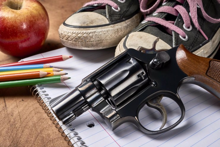 A gun next school supplies and an apple