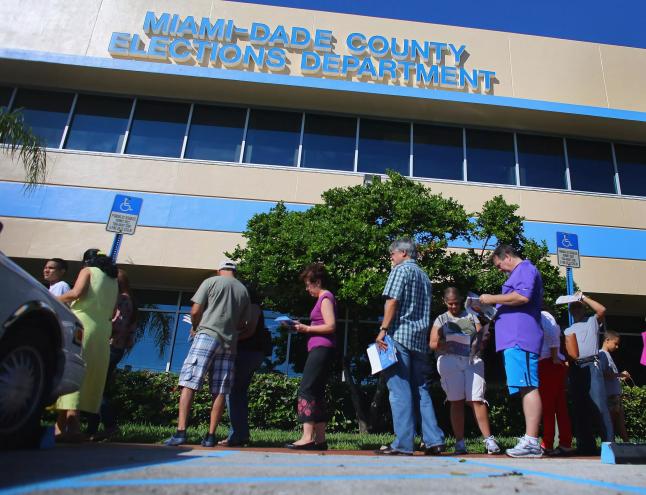 A small group of residents stand outside a county elections building