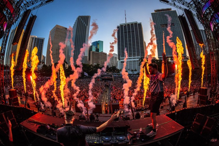DJ performing on the main stage at Ultra in front of a huge crowd against the downtown Miami skyline
