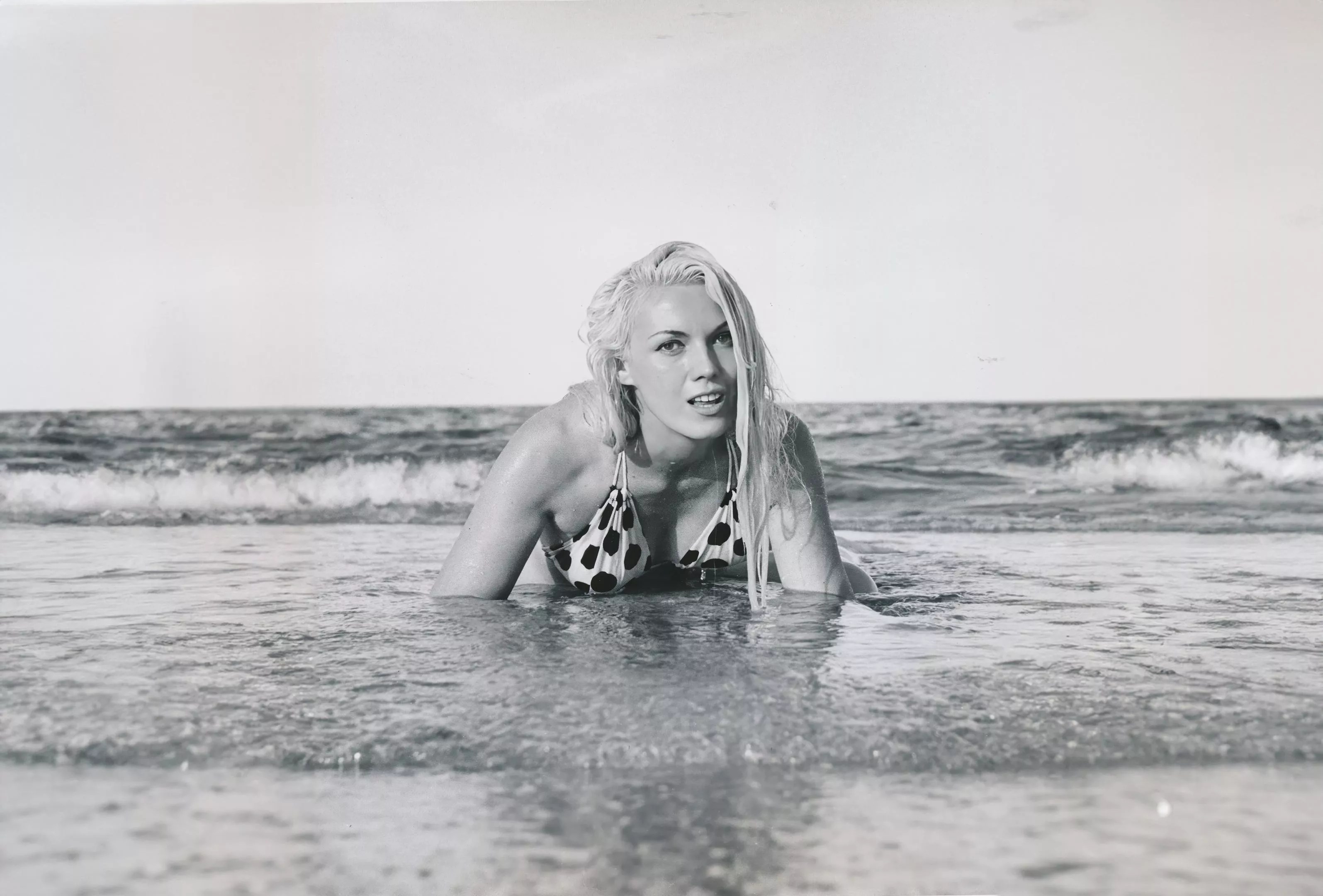 Bunny Yeager crawling out of the ocean onto the shore