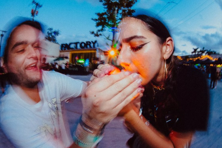 A man helping a woman light up a joint