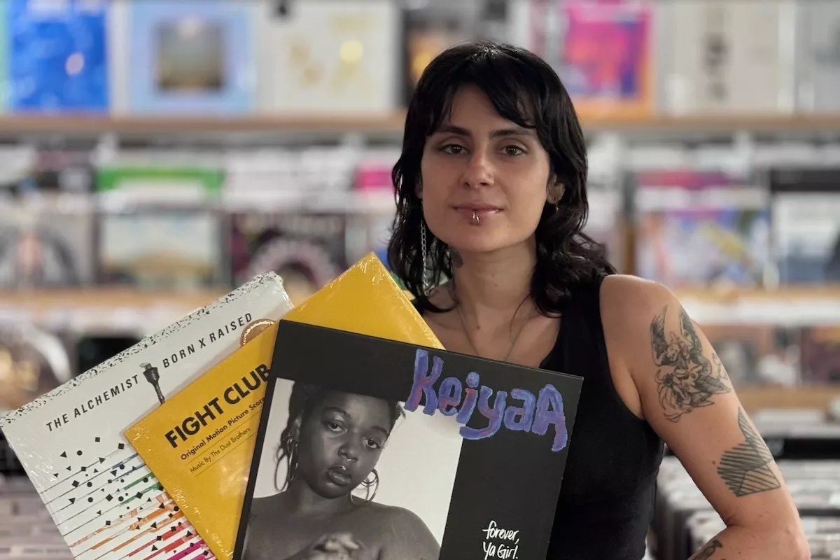 A woman holding three vinyl records in her hands