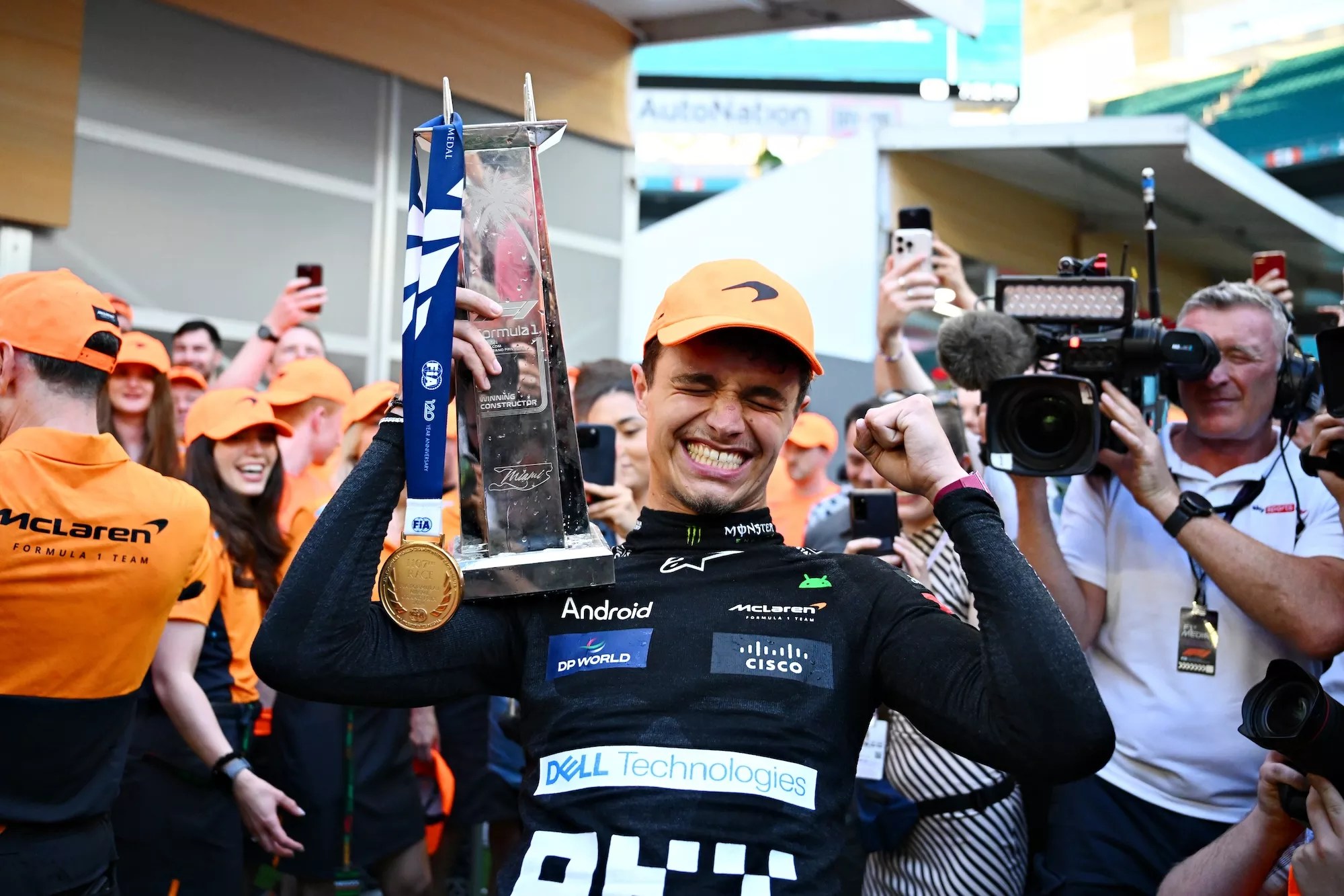Lando Norris holding his trophy surrounded by reporters