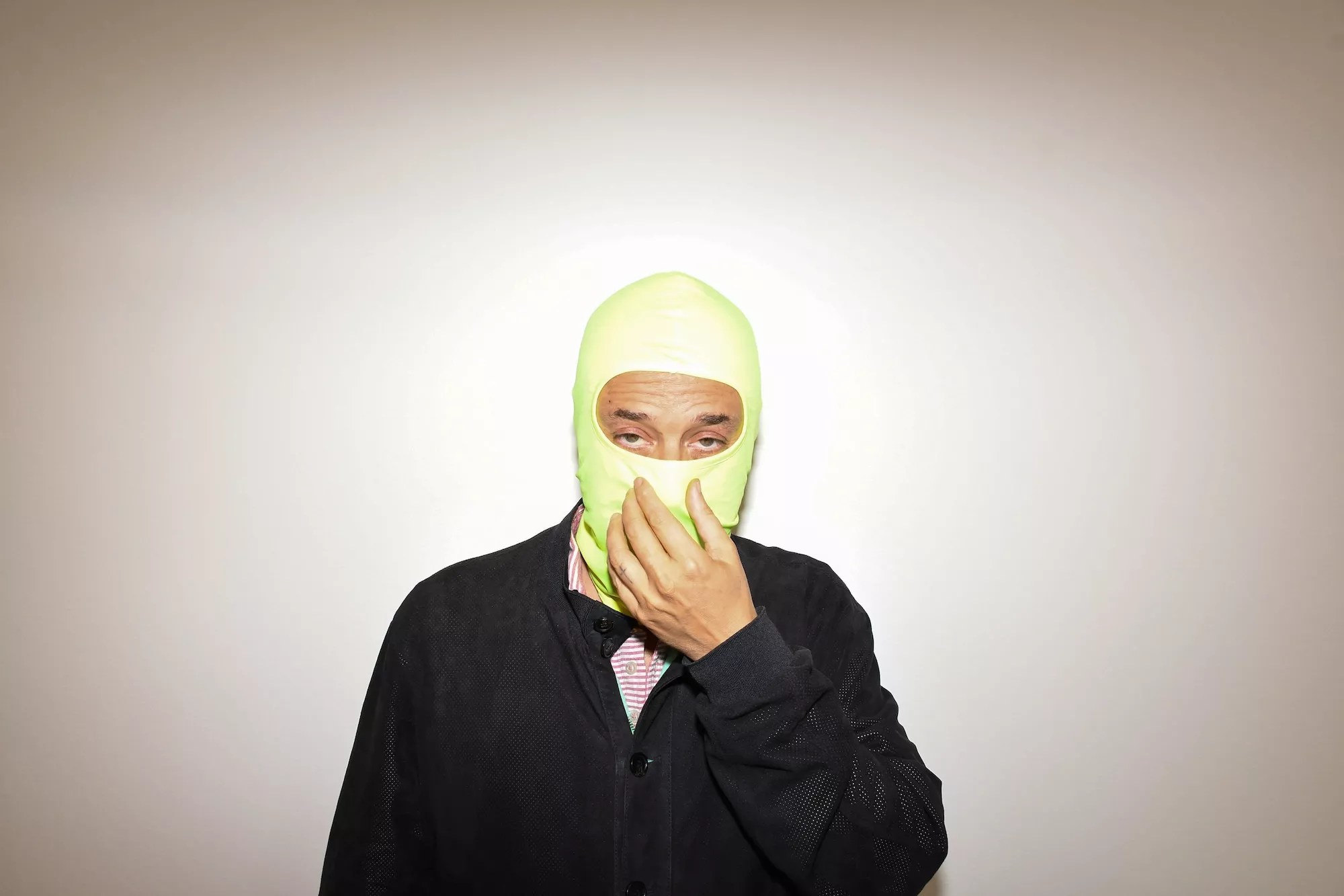 Harmony Korine, with his face covered by a neon-green balaclava