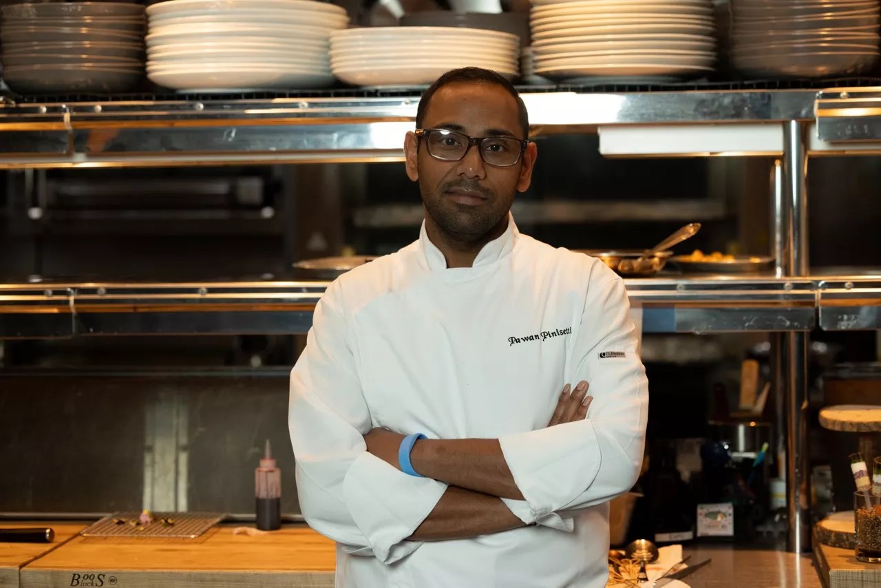 A chef in a white chef outfit posing