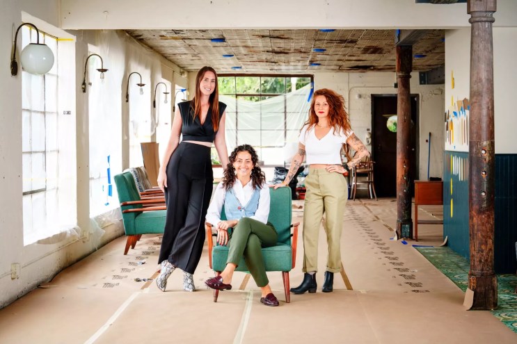 Three women posing for a photo in daylight in a building