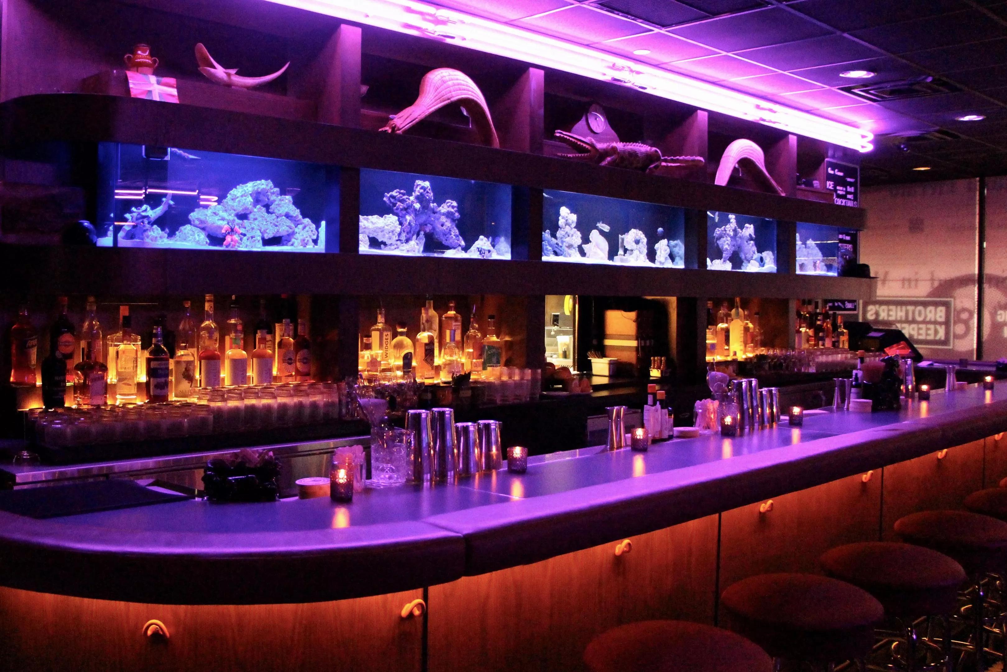 a bar with purple lights and red seating