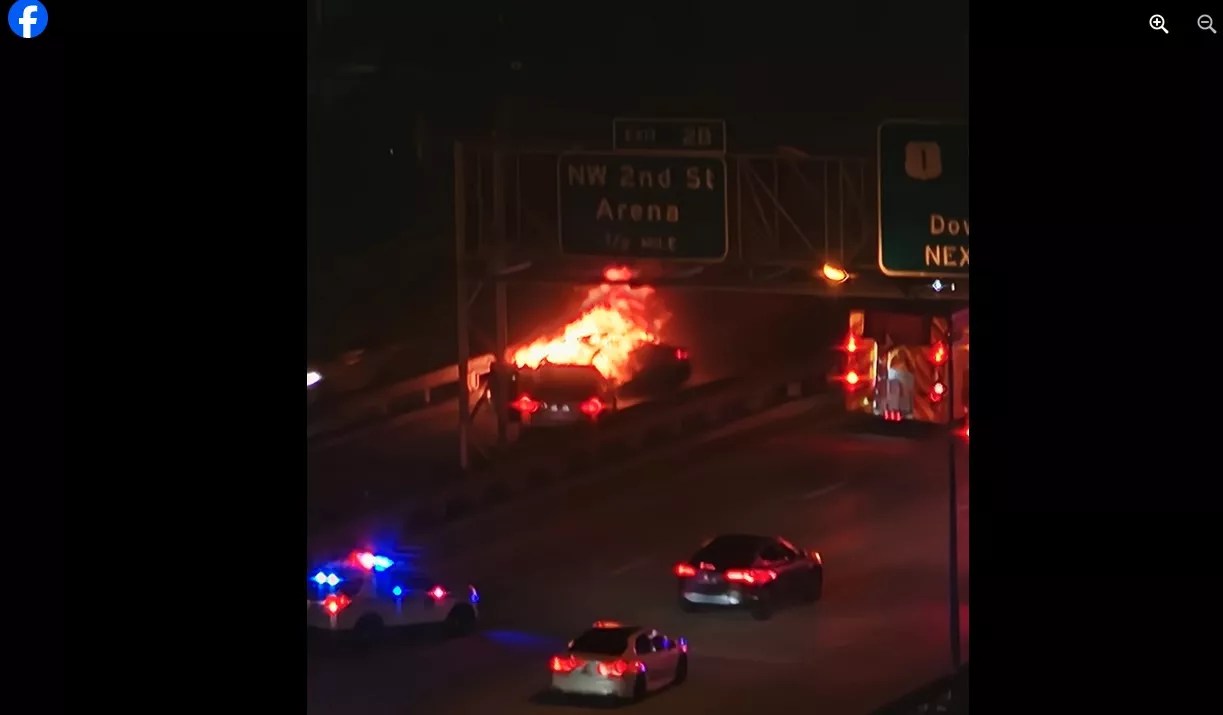A car engulfed in flames at night on I-95 in downtown Miami