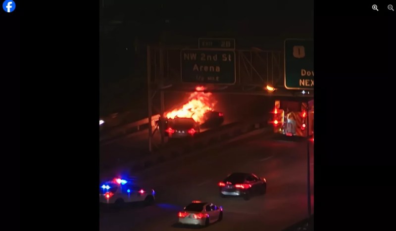 A car engulfed in flames at night on I-95 in downtown Miami