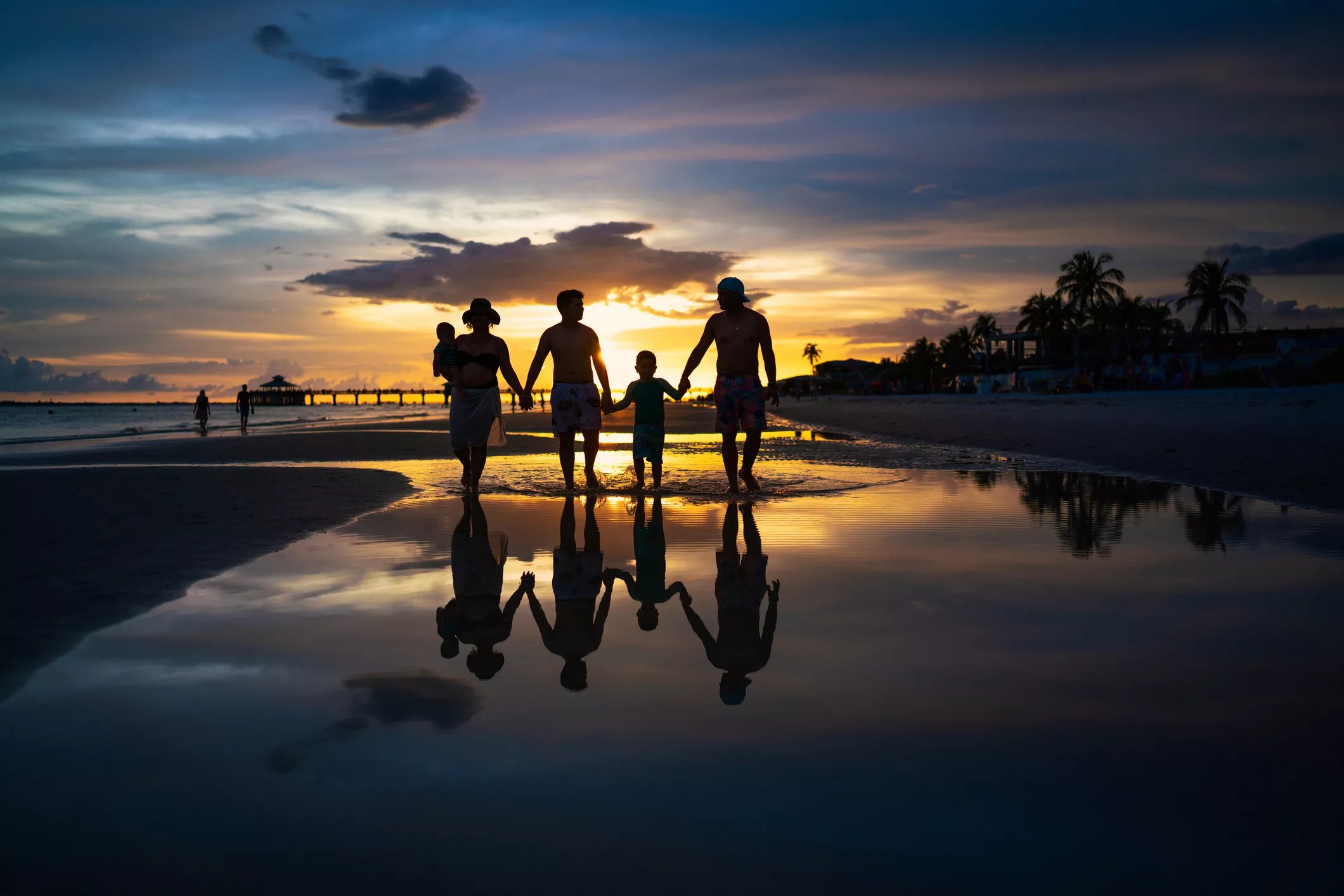A silhouette of a family walking on a beach at sunset