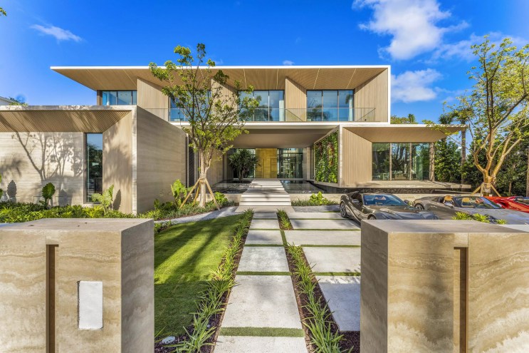 Long entryway to a Miami Beach mansion with a modern, boxy look and tropical landscaping