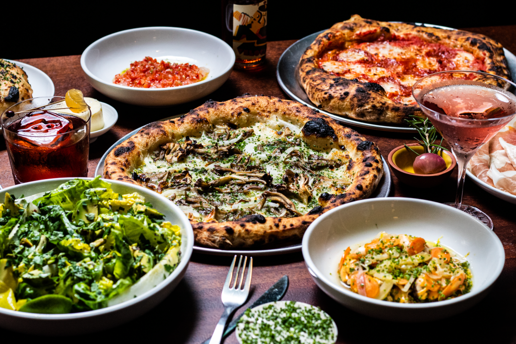 an array of dishes and pizzas on a wood table