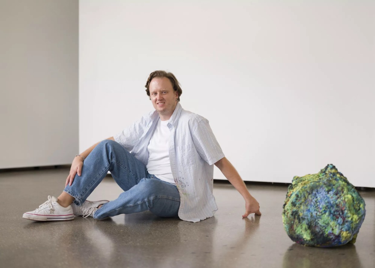 Portrait of artist Addison Wolff next to his artwork