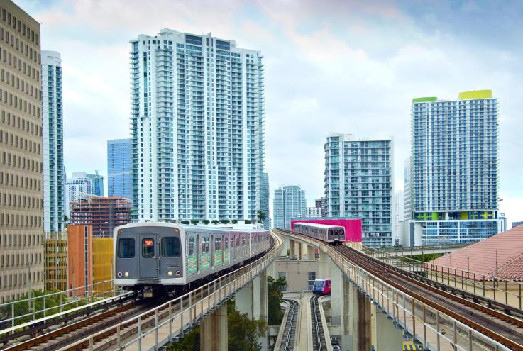 Two metro trains on elevated platforms with the Miami skyline in the background