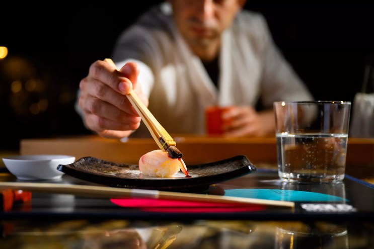 a man serving nigiri