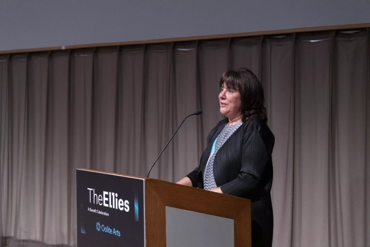 Maria Elena Angulo behind a podium, speaking at the Ellies Awards