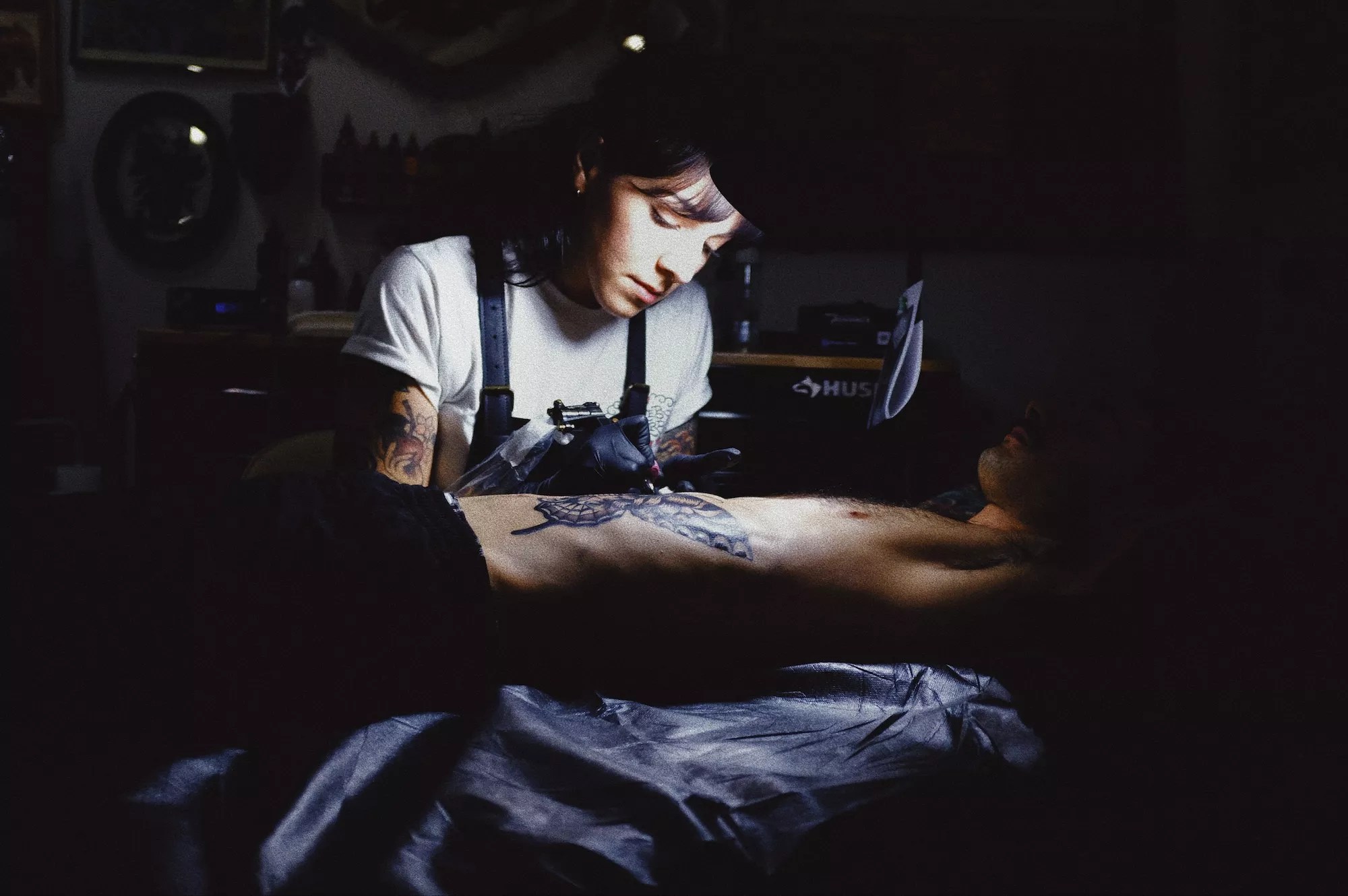 A woman tattooing a client