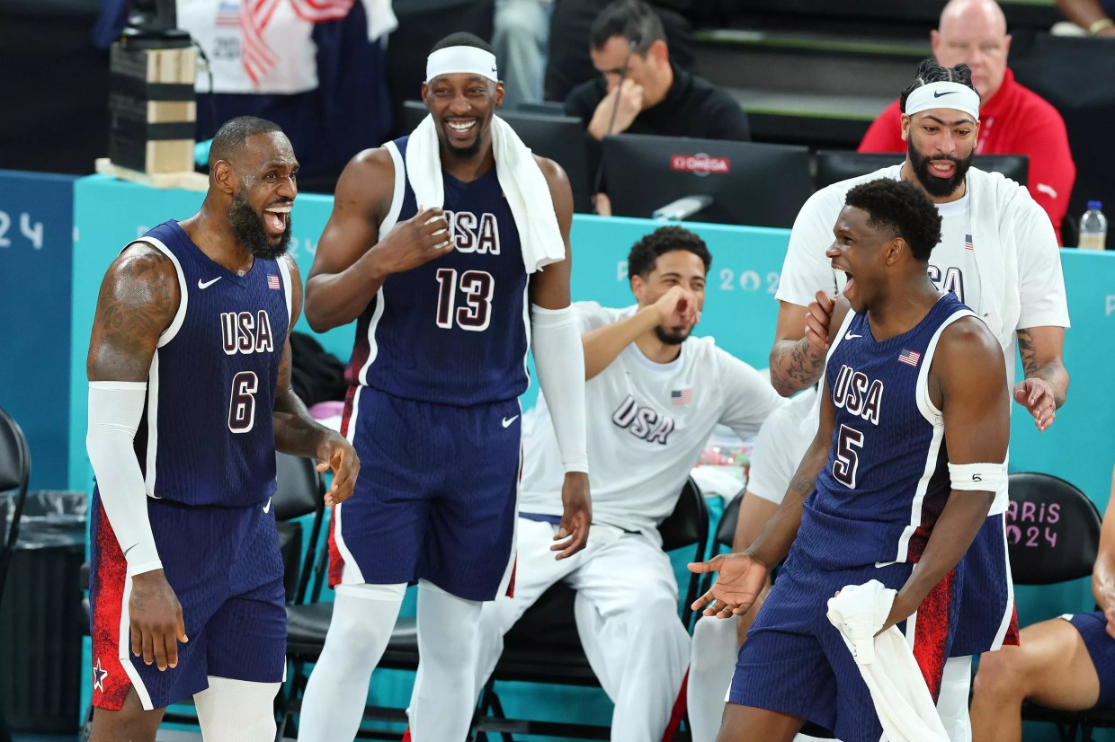 Lebron James, Anthony Edwards, and Bam Adebayo on the court, laughing and smiling near the sideline during a 2024 Olympics matchup