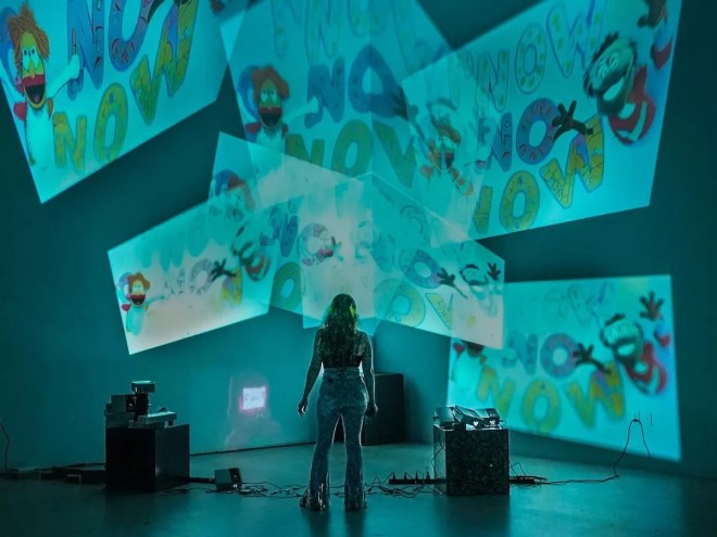 Haiiileen standing in front of massive projections on the wall